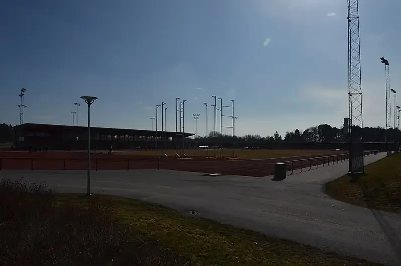 Tom friidrottsarena med löparbanor och belysningsmaster i skymningen